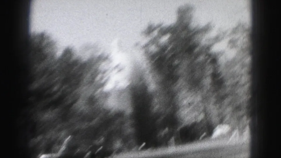 Motion-blurred 8mm frame from the Harrisburg clip showing trees, sky, and a dark foreground edge.