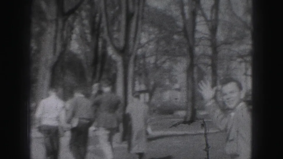 1975 Harrisburg 8mm frame showing a park path, distant figures, trees, and a domed building shape in soft focus.