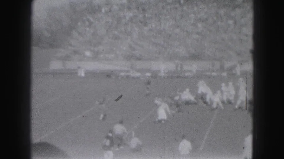 1975 Harrisburg football footage showing players after or during a play, with bleachers full of spectators behind them.