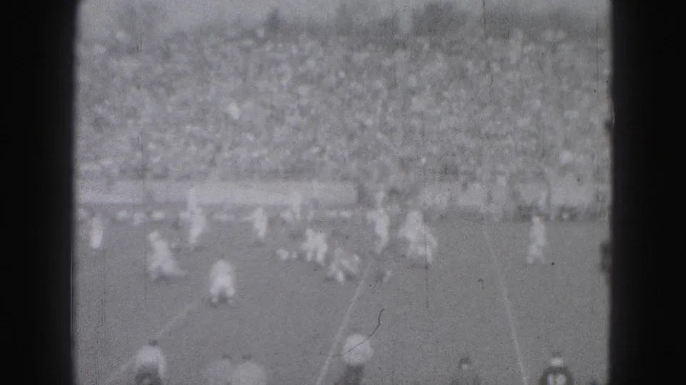 1975 Harrisburg soccer footage showing players spread across the field in front of packed bleachers, seen in soft black-and-white 8mm.