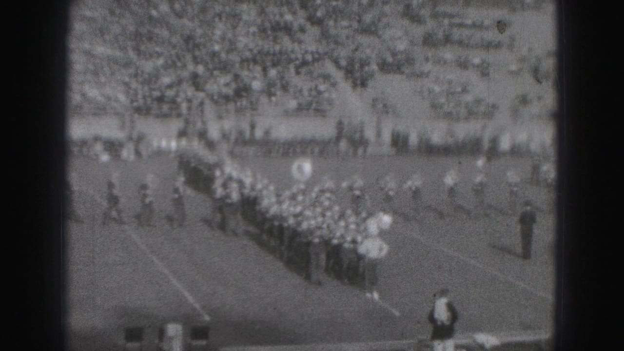 1975 Harrisburg stadium scene with a marching band in formation during a high school football event.