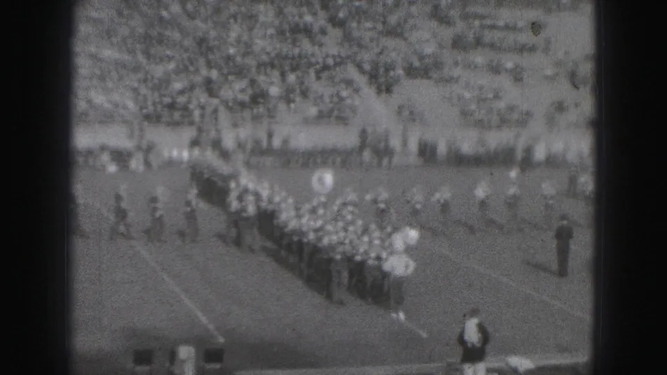 1975 Harrisburg stadium scene with a marching band in formation during a high school football event.