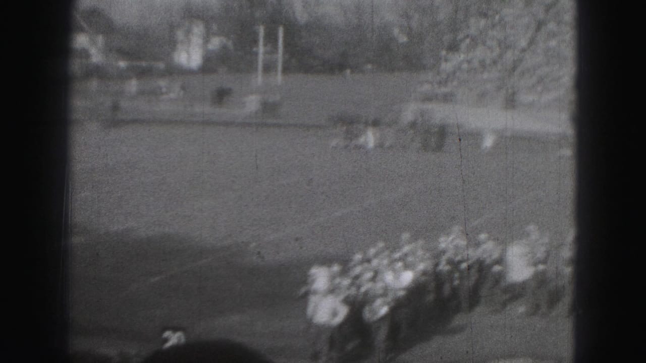 Distant Harrisburg, Pennsylvania 8mm view of band members grouped on a football field with open turf around them.