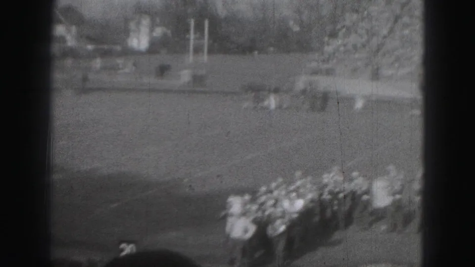 Distant Harrisburg, Pennsylvania 8mm view of band members grouped on a football field with open turf around them.