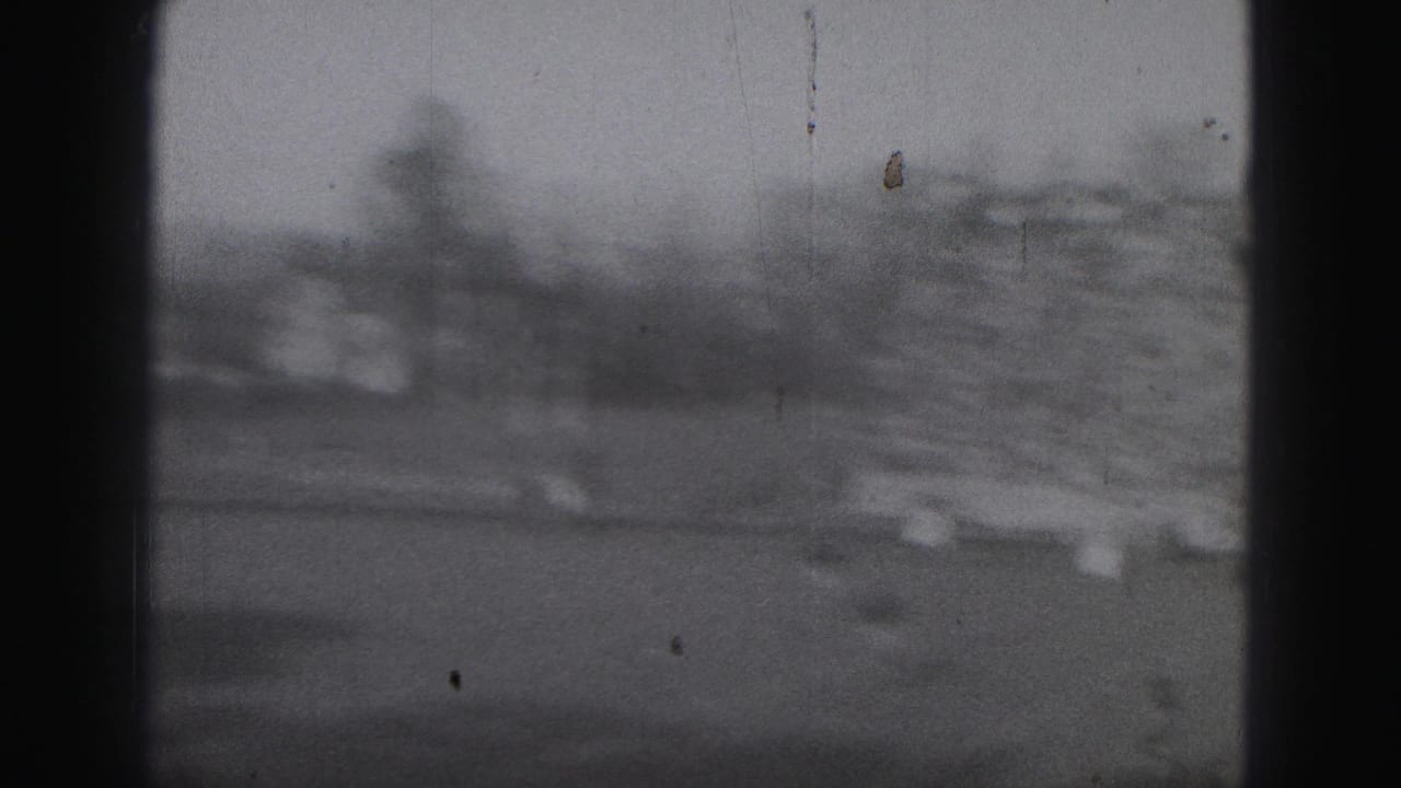 Blurred stadium crowd above a football field with dark vertical film borders.
