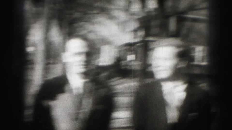A motion-blurred Harrisburg frame shows suited adult men close to the camera with residential buildings behind them.