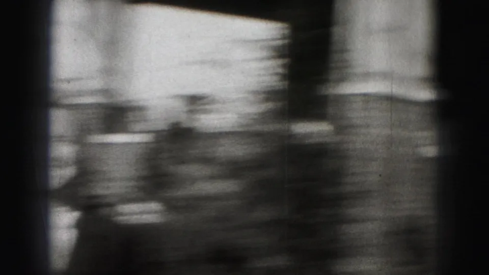 A motion-blurred home-movie frame shows a partial figure and soft residential background during the Harrisburg street scene.