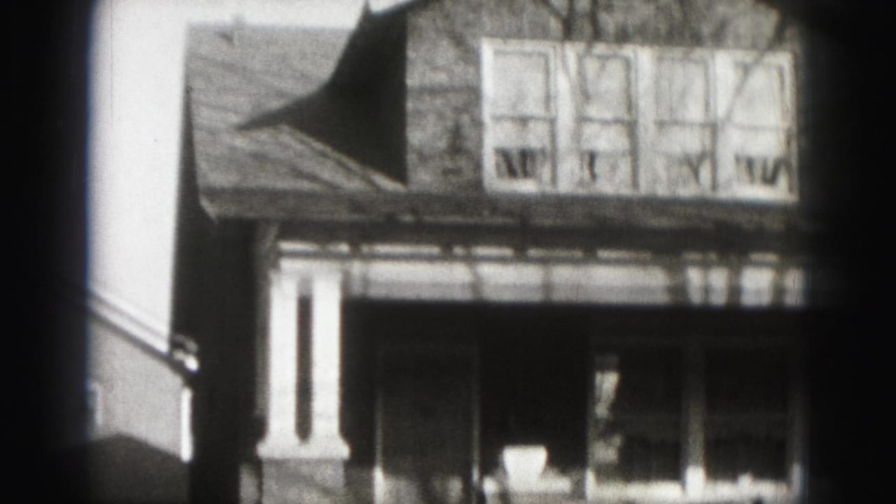 1975 Harrisburg home-movie frame showing a two-story suburban house facade with porch, brickwork, and four upper windows.