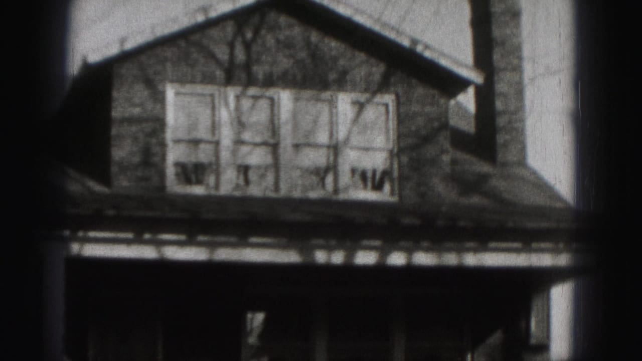 1975 Harrisburg frame centered on the upper facade of a suburban house, with four windows and dark porch area below.