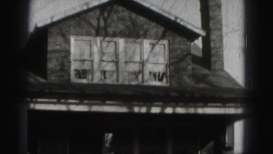 1975 Harrisburg frame centered on the upper facade of a suburban house, with four windows and dark porch area below.