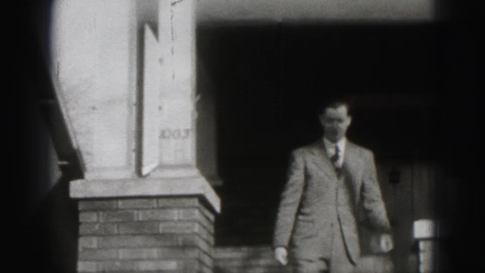 In Harrisburg, Pennsylvania, a suited man appears near the top of brick porch steps in 1975 home-movie footage.