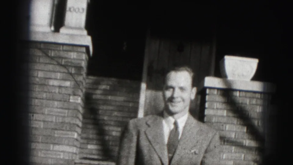 A closer 1975 Harrisburg frame shows the man smiling in sunlight with brick porch details behind him.