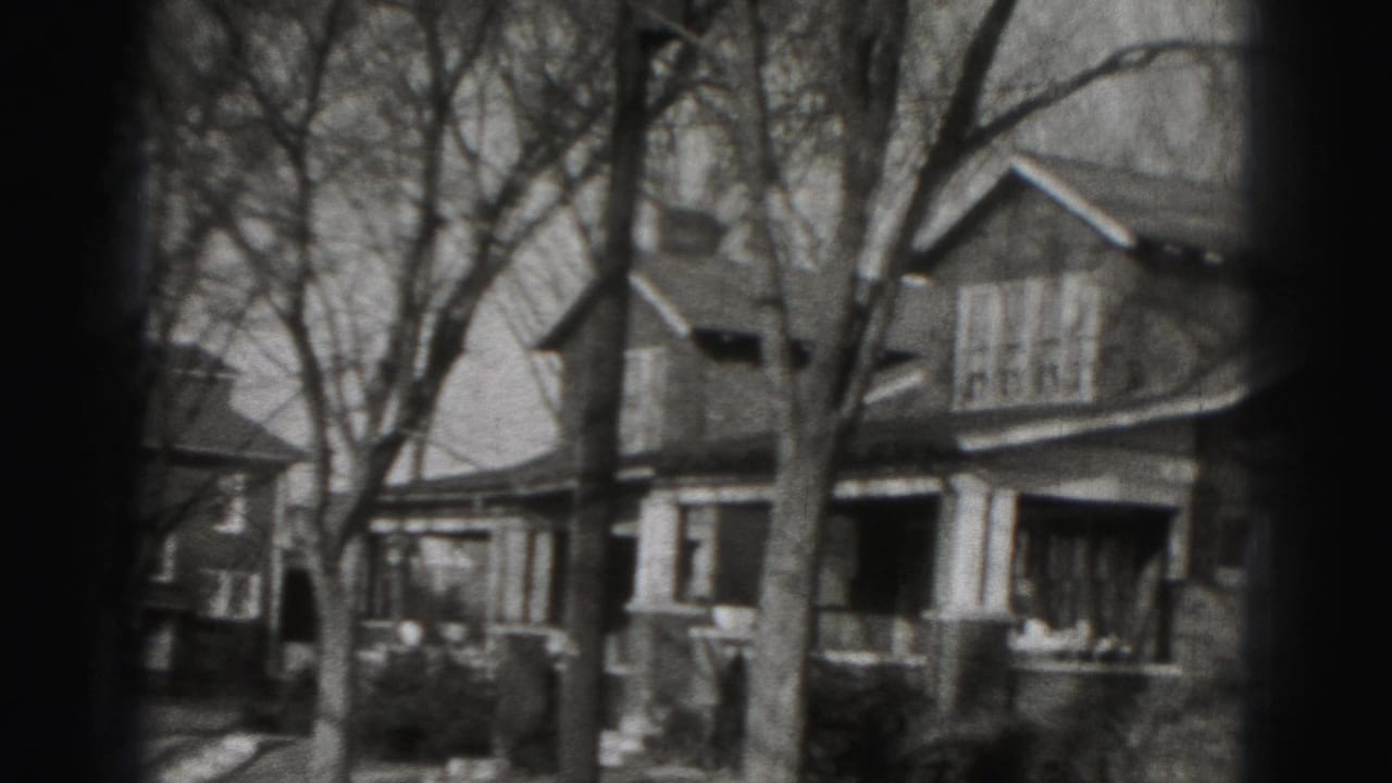 Two-story Harrisburg house exterior with front porch columns, peaked rooflines and leafless trees, filmed in 1975.