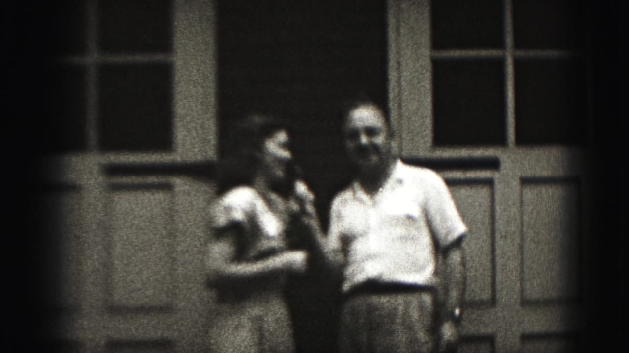 In 1975 Harrisburg home-movie footage, a woman and man stand before paneled doors as she holds a microphone near them.
