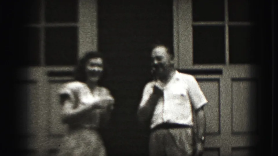 The woman appears to laugh or speak into the shared microphone while the man stands nearby in Harrisburg, Pennsylvania footage from 1975.