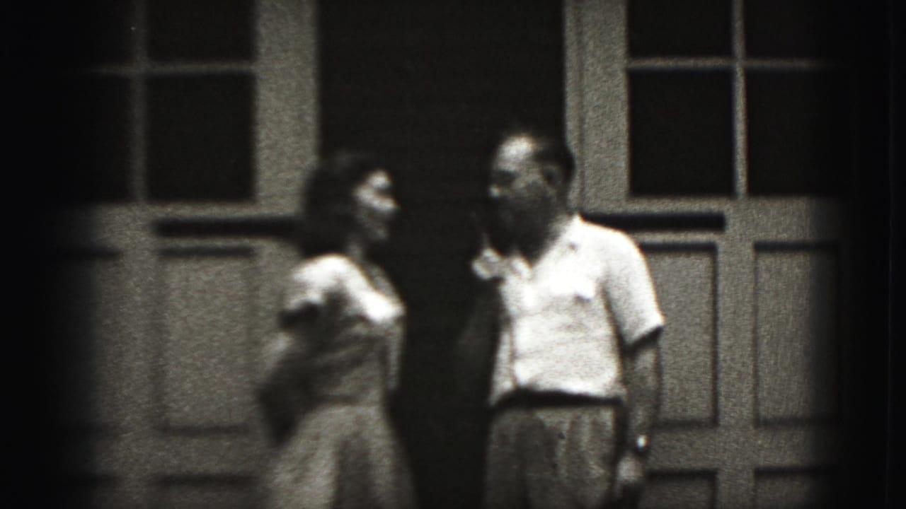 Woman and man face each other outside a building with paneled doors.