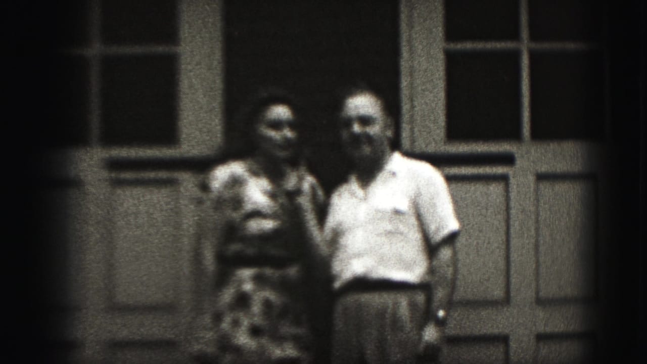 Man and woman stand close together in front of paneled doors.