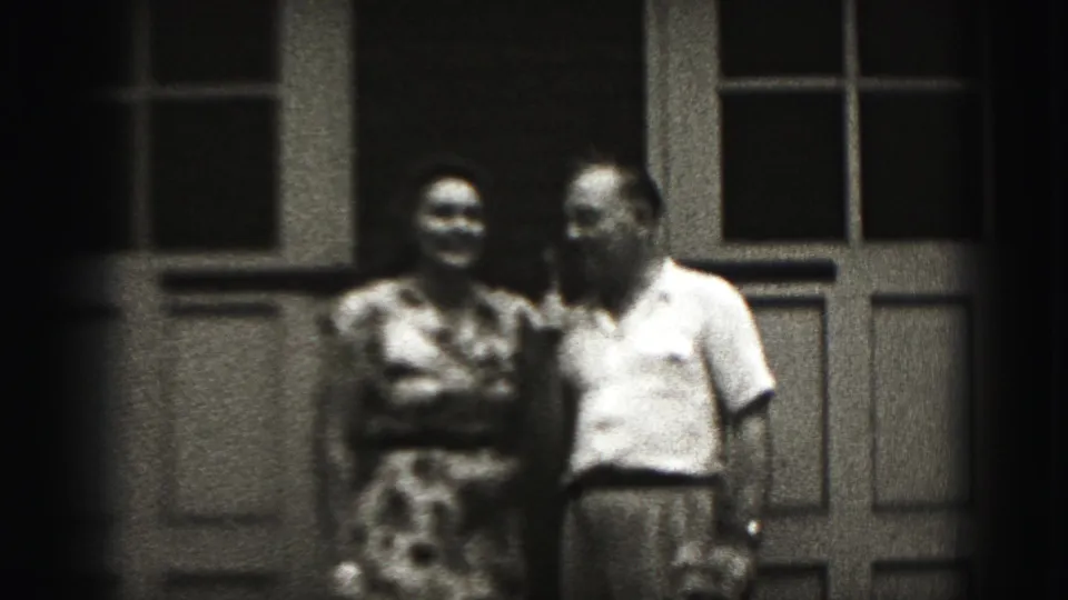 The woman smiles while standing beside the microphone-holding man in this soft 8mm Harrisburg exterior shot.