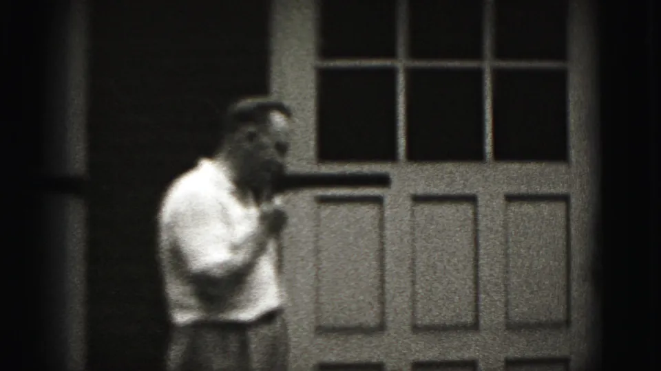 Near the end of the Harrisburg clip, the man turns in profile while pacing across the doorway in black-and-white 8mm footage.