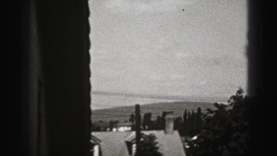 A window-framed view looks across rooftops, trees, and distant hills in Harrisburg, Pennsylvania, 1975 footage.