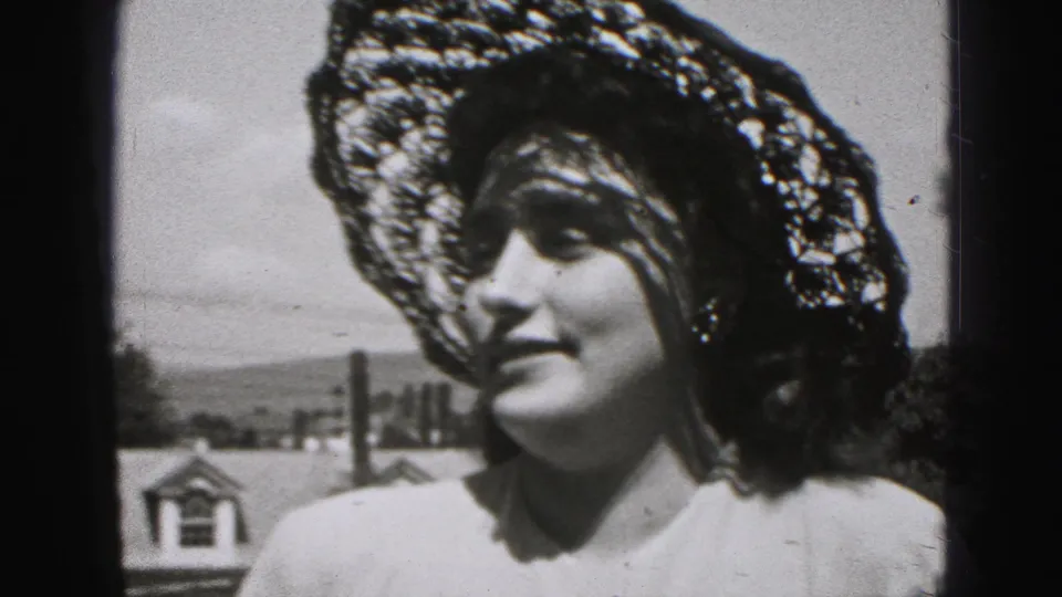 Woman in a wide lace-style sun hat smiles while looking off to the side in Harrisburg, Pennsylvania, 1975.