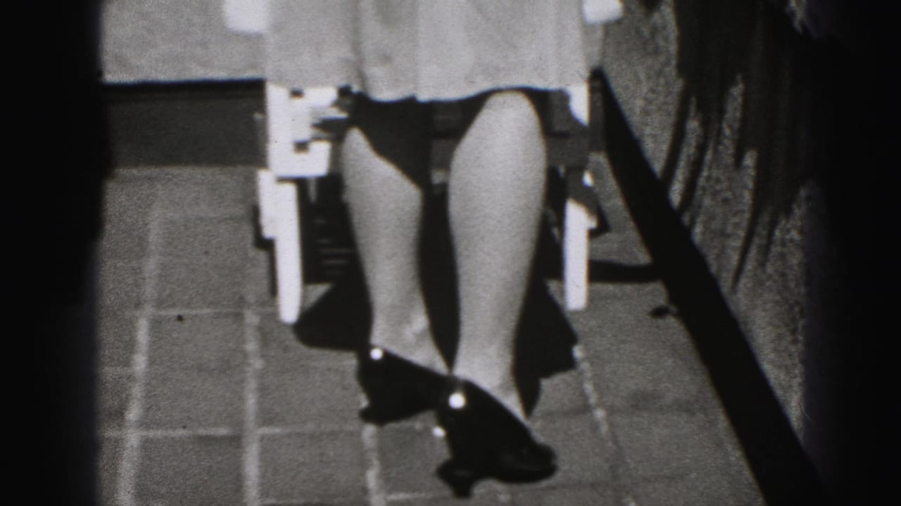 Lower half of a woman in a light dress walking near a white outdoor chair.