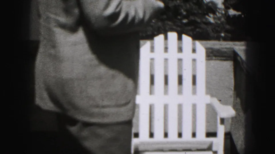 The man is seen from behind in a suit, moving past a white chair in the Harrisburg residential setting described by the metadata.