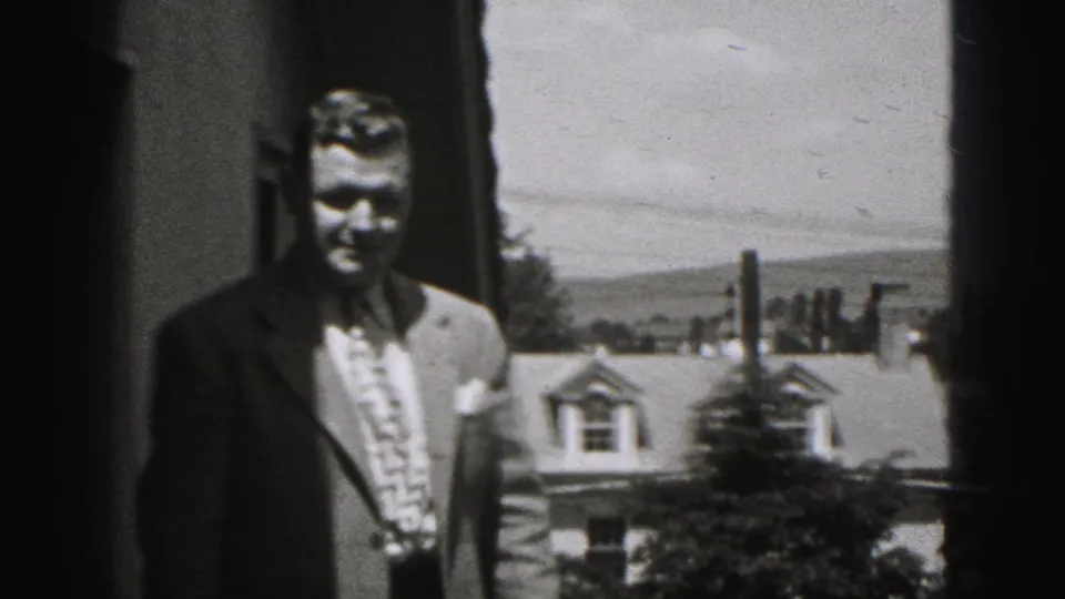 In this 1975 Harrisburg frame, a man in a suit and patterned tie faces the camera from an upper exterior space.