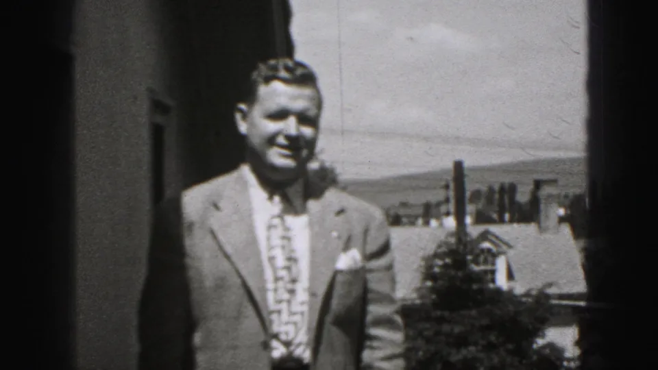 A smiling adult man in a light suit and patterned tie is filmed on a balcony or patio in Harrisburg, Pennsylvania.
