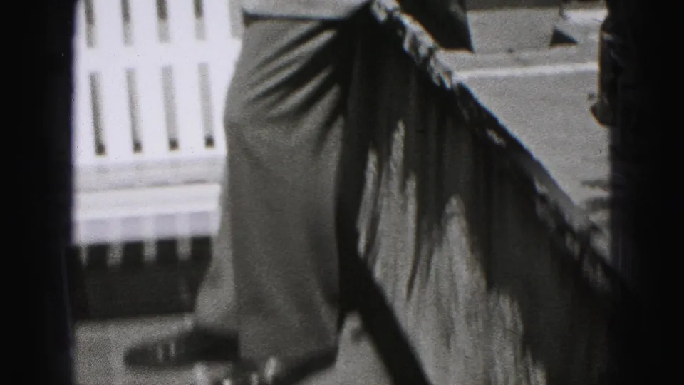 A side view captures the suited man beside a white fence in the 1975 Harrisburg residential outdoor scene.