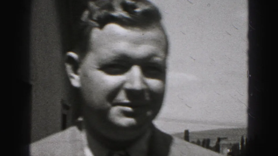 A close 8mm frame shows the man’s face and suit as he nears the camera in the Harrisburg, Pennsylvania, 1975 clip.