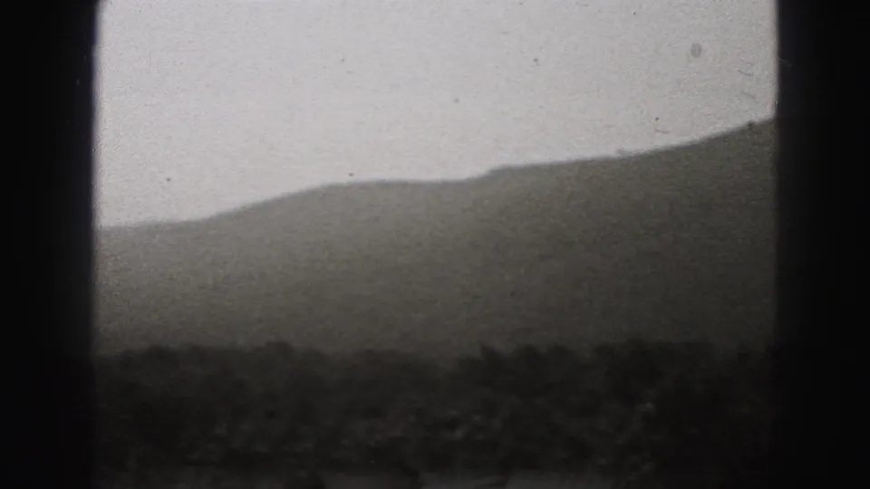 Soft-focus 1975 Harrisburg-area home-movie view of a hillside, dark foreground, and pale sky within 8mm borders.