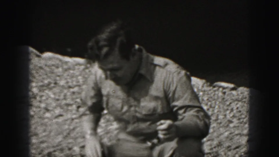 The man crouches outdoors on gravel in the Harrisburg 1975 home-movie clip, looking down as the puppy moves out of clear view.