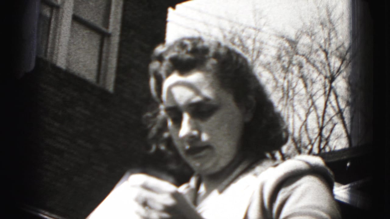 Young woman outdoors near a brick building, looking down while holding paper.
