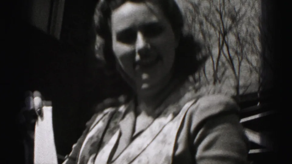 Close handheld view of the woman outside in Harrisburg, with her face partly in shadow and bare trees behind her.