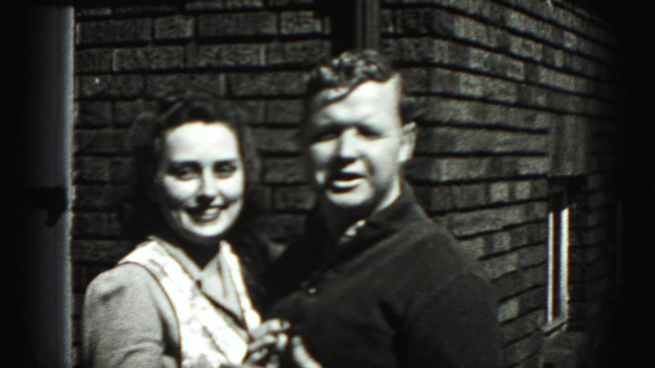 Woman and man smile and pose together against a brick wall.