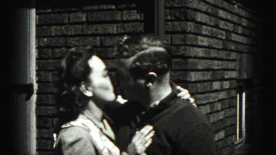 The adult couple share a kiss and embrace in the 1975 Harrisburg home-movie scene.