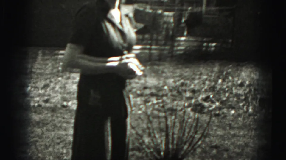 1975 8mm frame from Harrisburg showing a woman outdoors in a field, partly cut off by the film edge and exposure shift.