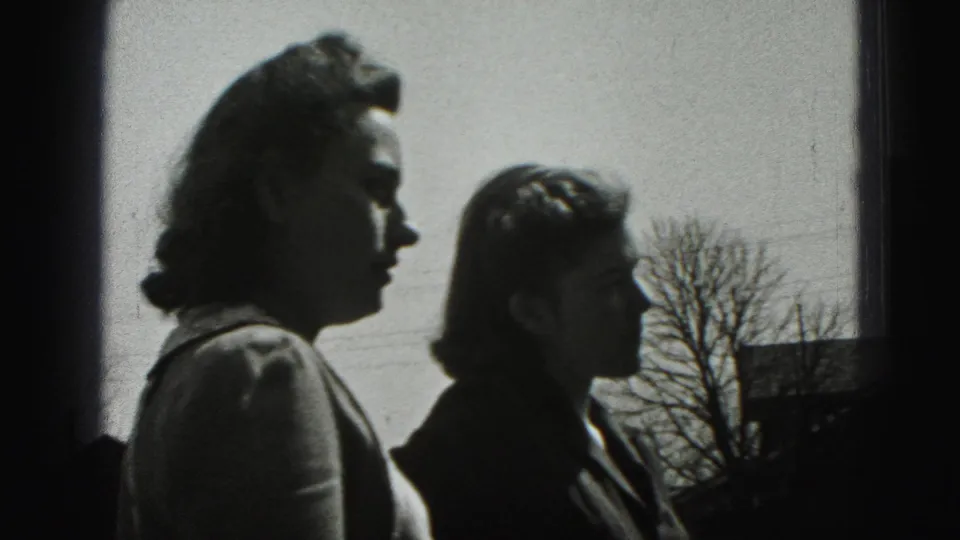 Two women stand in profile outdoors in Harrisburg, Pennsylvania, with a field, bare tree, and bright sky behind them.