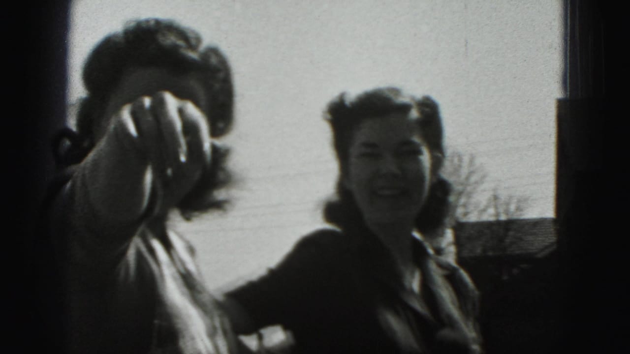 In 1975 Harrisburg home-movie footage, two adult women stand outside as one gestures near the lens and the other smiles.