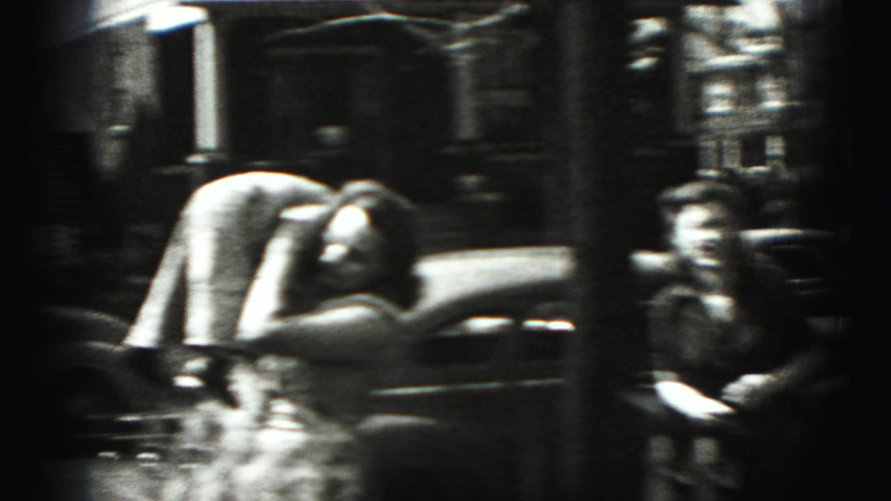 Two figures near a parked car on a residential street, one bent forward in motion.