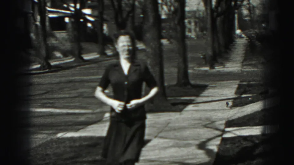 Adult woman faces the camera on a Harrisburg sidewalk, framed by bare trees and a quiet residential street.