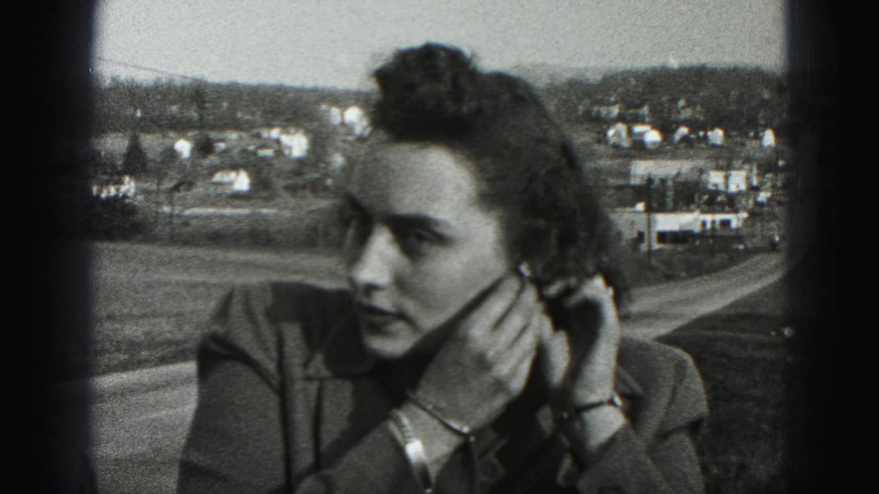 Woman outdoors adjusting an earring with a road and distant houses behind her.