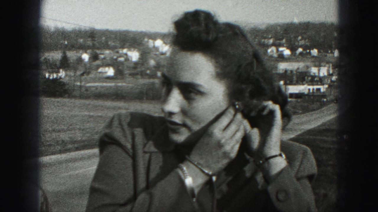The woman turns in profile while holding her earring, with a Harrisburg-area road and distant homes visible behind her.