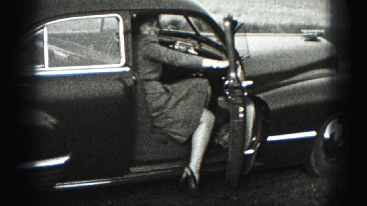 The woman steps into the older sedan in the 1975 Harrisburg home-movie scene, partially turned away from the camera.