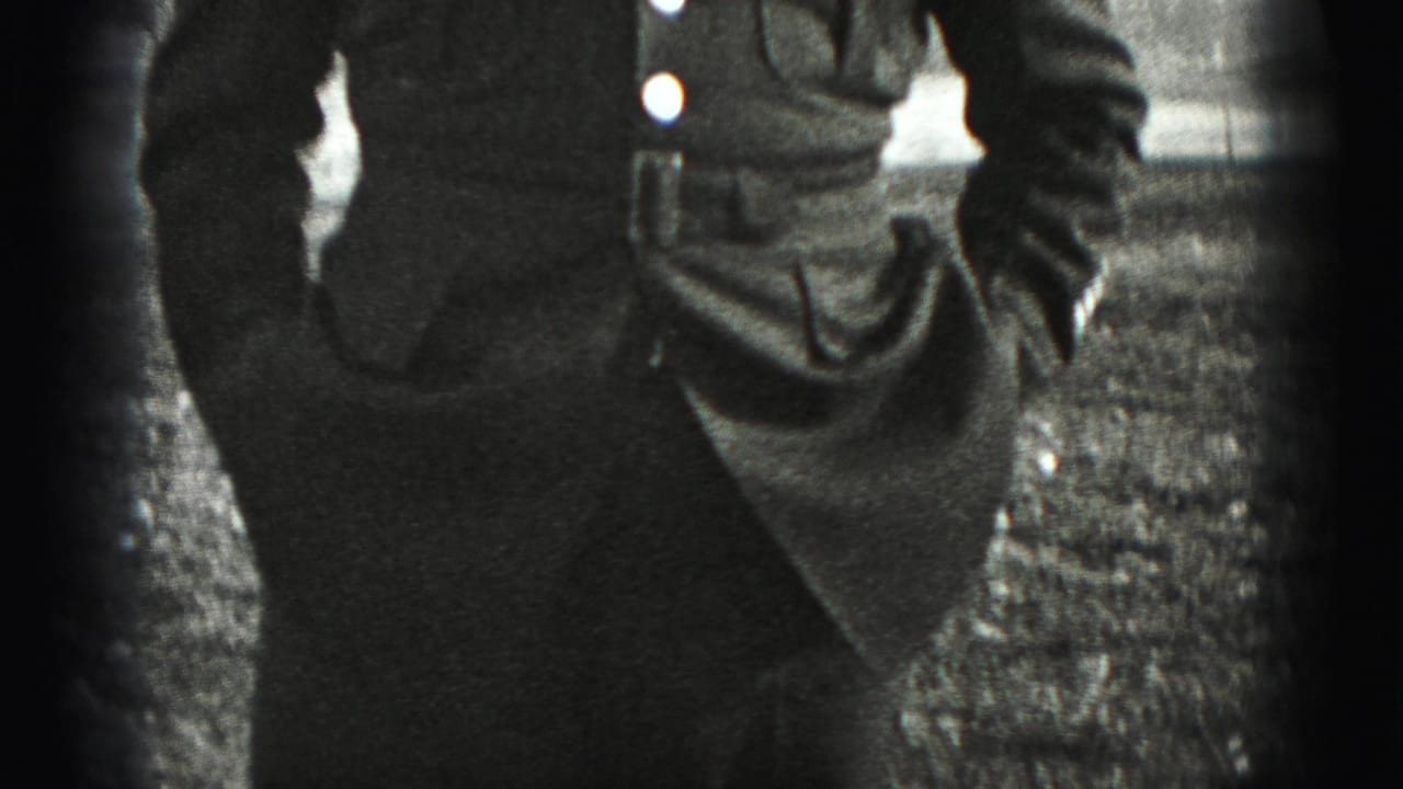 Close, cropped view of a uniformed torso and arm beside rough ground.
