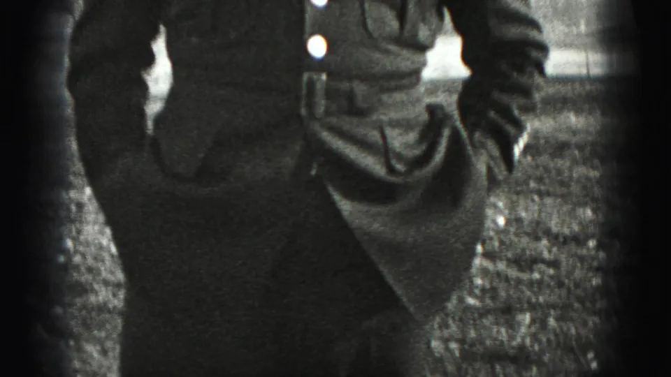 Cropped 1975 home-movie frame showing part of the uniform jacket, sleeve, and outdoor ground in Harrisburg, Pennsylvania.