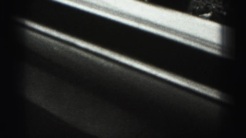 Final 8mm frame shifts away from the subject to a dark, close view that appears to show a car door or interior window edge.
