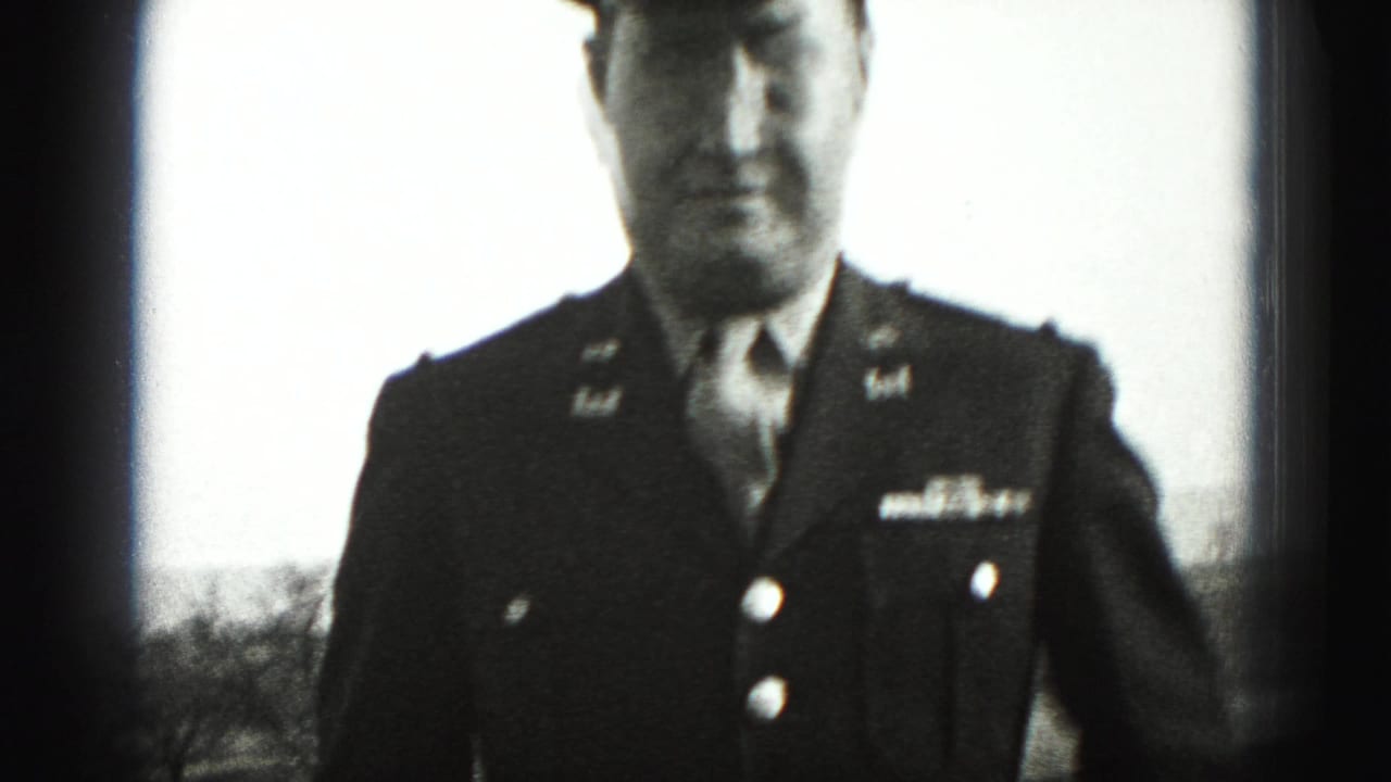 Uniformed adult man standing close to the camera in a dark military jacket.