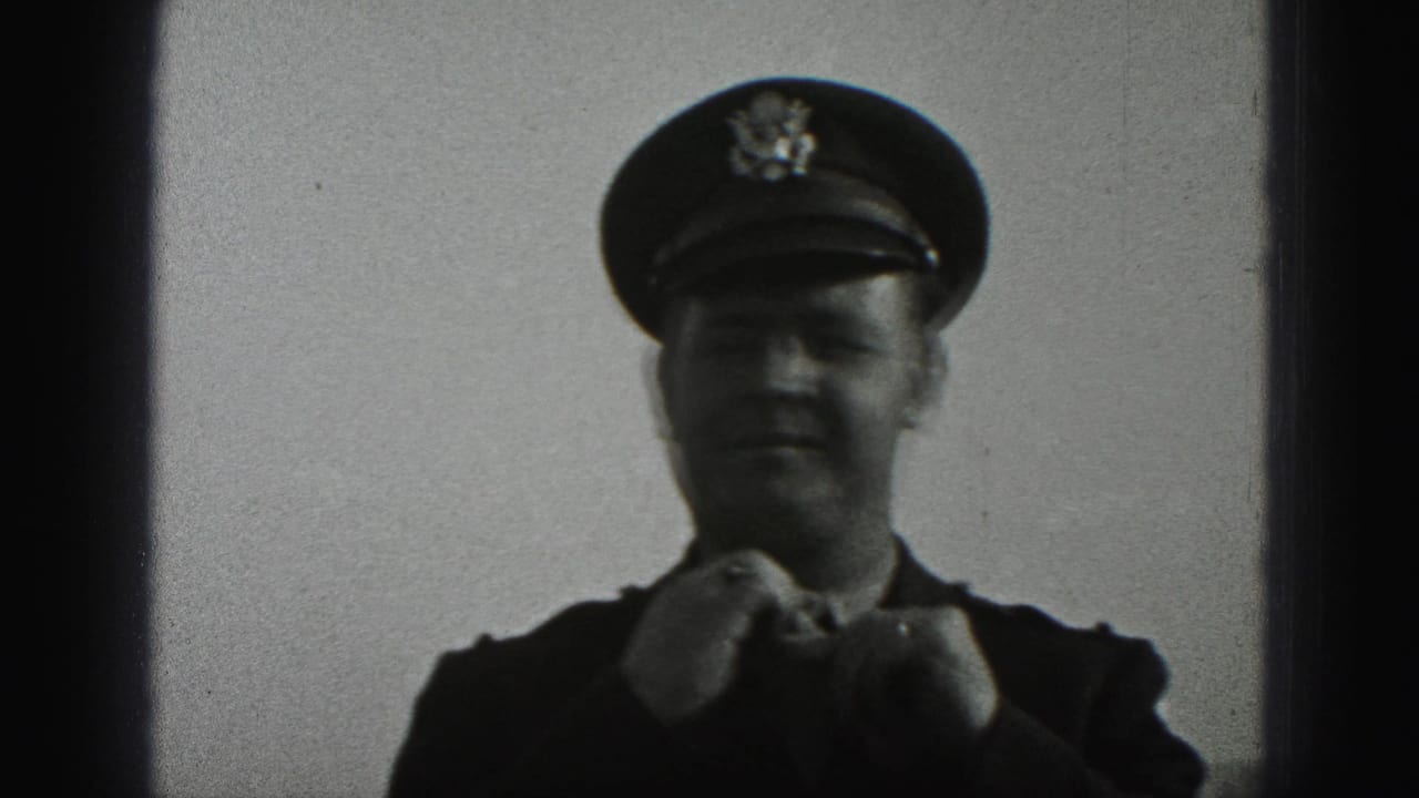 A uniformed adult man in a peaked cap appears to adjust his tie in the 1975 Harrisburg 8mm footage.